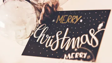 Card with “Merry Christmas” in front of decorative glass balls