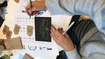Hands write on paper to make Christmas cards