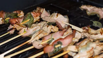 Grilled skewers with meat and bacon on a grill.