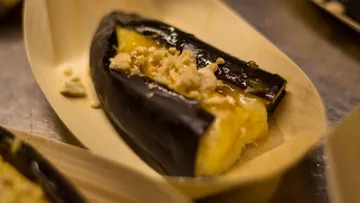 Roasted eggplant with sweet filling on a wooden plate.