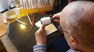 Handwerker bearbeitet Holzplatte mit Hammer auf Werkbank.