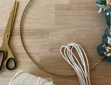 Golden ring with rope and scissors on wooden table.