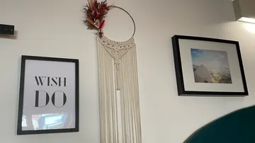 Wall decoration depicts macrame and two framed pictures.
