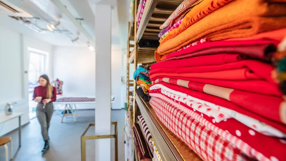 Stacks of colorful fabrics while a person stands in the background.