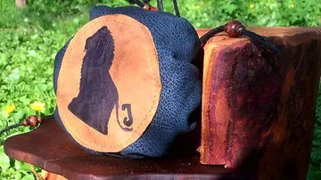 Round decorative bag sits next to a block of wood.