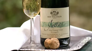 Flasche Sekt steht neben einem Glas auf einem Tablett.