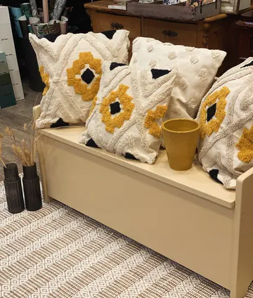 A sofa with decorative pillows and a flower pot.