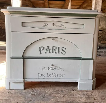 There is a drawer cabinet with Paris inscription in a room.