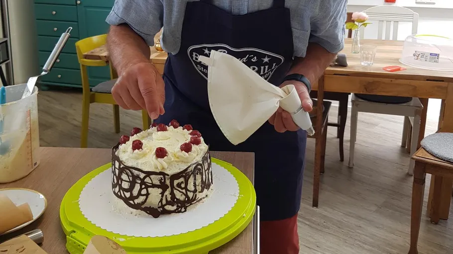 Person decorating cake in kitchen setting.