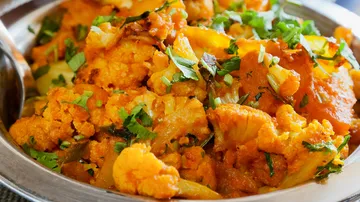 Cauliflower dish in a bowl, seasoned and garnished with herbs.