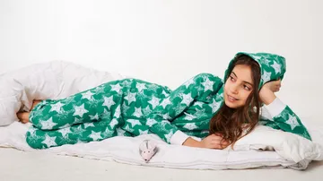 A girl is relaxing on a bed with blankets.