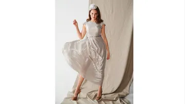 Woman wearing an elegant dress against a neutral background.