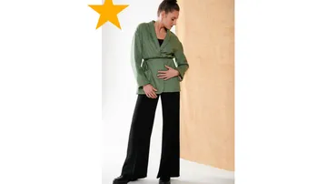 Woman in green outfit poses against orange background.