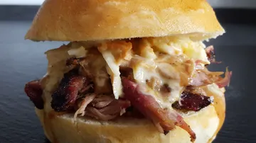 Burger mit Fleisch und Sauce, auf einem schwarzen Hintergrund.