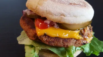 Burger mit Käse, Salat und Gemüse auf einem Teller.