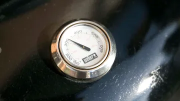 A thermometer shows the temperature of a grill.
