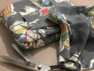 Stoff liegt gefaltet neben einer Schere auf der Fläche.