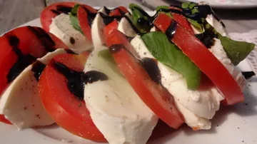 Tomate und Mozzarella sind geschichtet, mit Balsamico beträufelt.