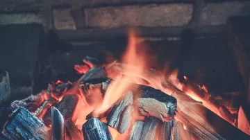 Glowing coals blaze in a cozy fireplace.