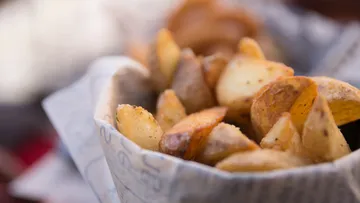 Potato wedges lie in a paper bag on a table.