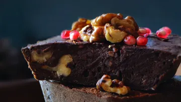 Chocolate cake decorated with nuts and pomegranate seeds.