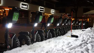 Nine Segways are parked in the snow at night.