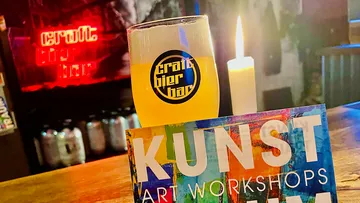 Bierglas steht vor einer Kerze und einem Flyers.