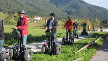 Groups of people ride on Segways in nature.
