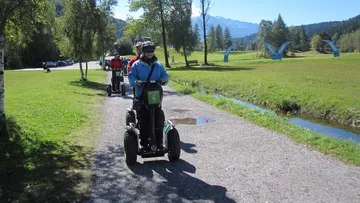 Segway-Fahrer bewegen sich auf einem Weg durch eine Parklandschaft.