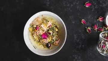 Schüssel mit Kräutermischung und getrockneten Rosenblüten.