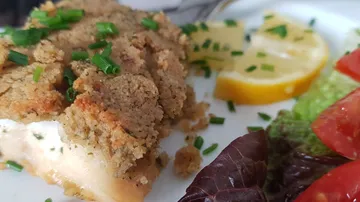 Fischfilet mit Bröselkruste und frischem Salat auf dem Teller.