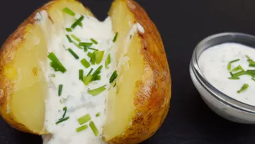 Gebackene Kartoffel mit cremigem Dip und Schnittlauch dekoriert.