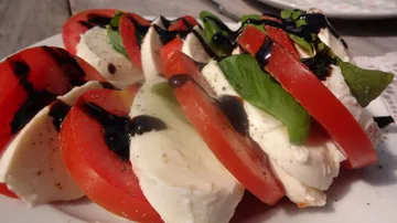 Tomaten und Mozzarella sind geschichtet, mit Balsamico und Basilikum.