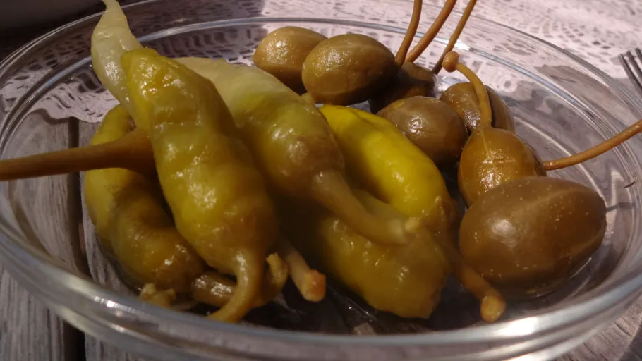 Gelbe Chilis und Oliven in einer Schale auf einem Tisch.