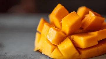 Reife Mango, gewürfelt, liegt auf einer grauen Oberfläche.