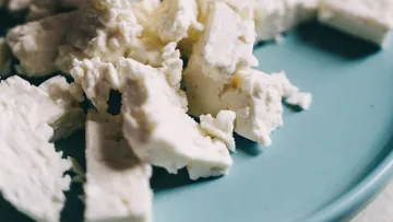 Zerbröckelter Käse liegt auf einem blauen Teller.