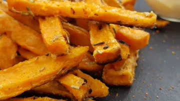 Sweet potato fries are stacked on a plate.