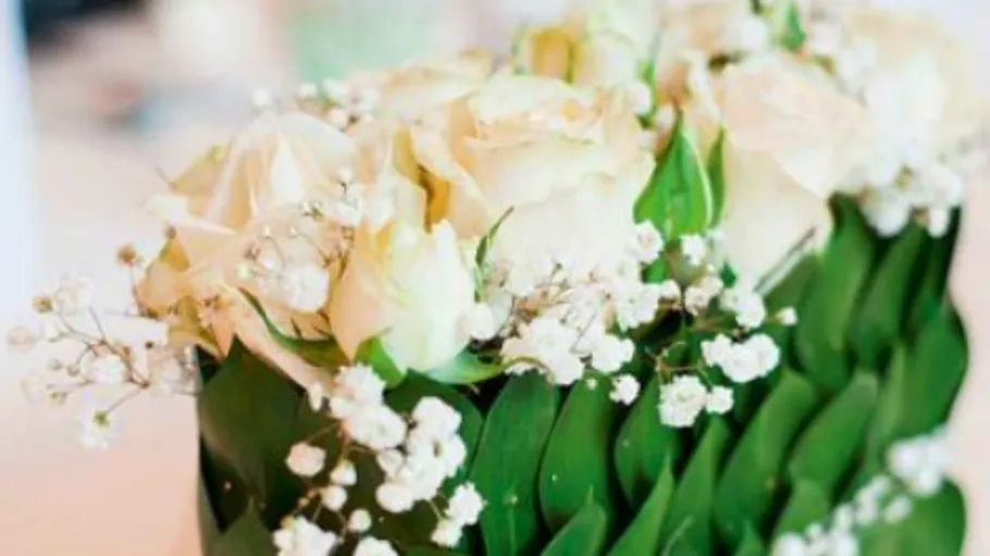 Weiße Rosen in einer dekorativen grünen Vase.