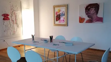 Ein Tisch mit Stühlen in einem kunstvollen, hellen Raum.