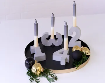 Candles stand in numbers on a round black tray.