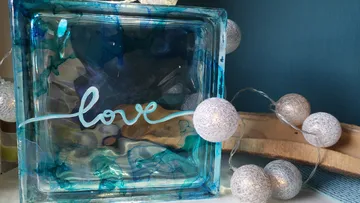 Blaues Glas mit „love“, umgeben von Lichterketten.
