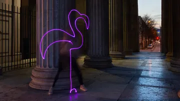 Flamingo light figure moves between pillars in the city.