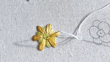 Embroidered flower on light fabric, thread connects them