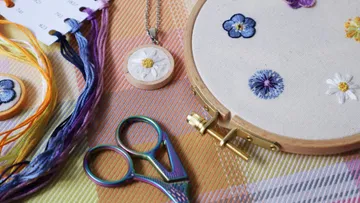 Embroidering floral motifs on fabric with accessories.