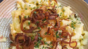 Kartoffelbrei mit knusprigen Zwiebeln und Schnittlauch garniert.