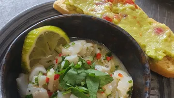Bowl of fish, lime and bread with avocado spread.