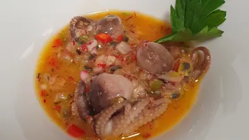 Octopus pieces in spicy sauce with vegetables and herbs.