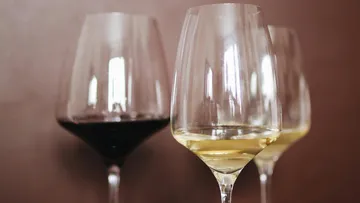 Three wine glasses stand together on a table.