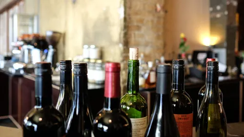 Weinflaschen stehen in einer Bar, umgeben von Glassware.