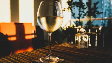 Wine glass is on a table, light shines in.